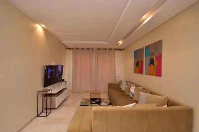a living room with a couch and a tv at Appartement Prestigia Golf City Marrakech in Marrakech