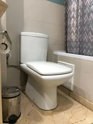 a white toilet in a bathroom with a shower curtain at MAJORELLE APPARTEMENT FAMILIAL in Marrakech