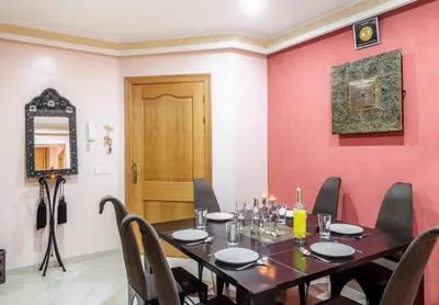a dining room with a table and chairs and a red wall at MAJORELLE APPARTEMENT FAMILIAL in Marrakech