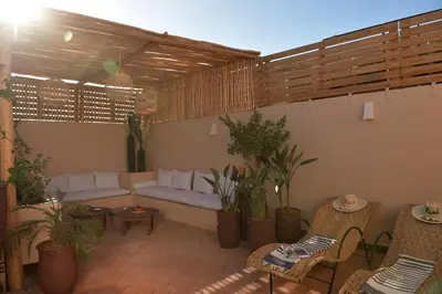 a patio with a couch and chairs and plants at Riad Palau Marrakech in Marrakech