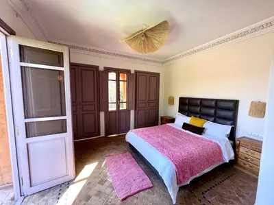 a bedroom with a large bed with a pink blanket at Villa 1 by Majestic Properties in Marrakech