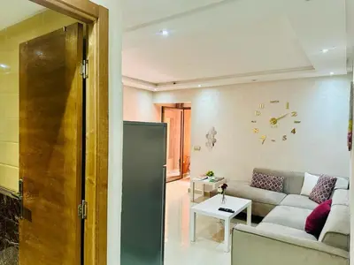 a living room with a couch and a clock on the wall at Chic & Lovely Flat in City Center in Marrakech