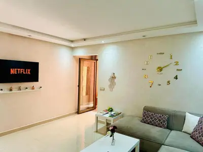 a living room with a couch and a clock on the wall at Chic & Lovely Flat in City Center in Marrakech