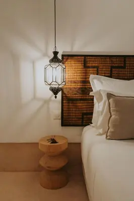 a bedroom with a bed with a lamp and a wooden table at Riad Babel au coeur de la Médina in Marrakech