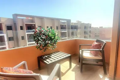 a balcony with a table and a plant on a window at appartement chic haut standing centre gare in Marrakech