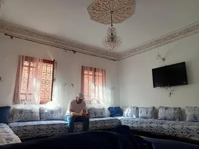 a man sitting on a couch in a living room at Nahe Park Issil und Marjane. Yoga auf Anfrage. in Marrakech