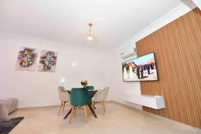 a living room with a table and a tv on a wall at appartement luxueux /confort , l’hivernage(Guéliz) au cœur de Marrakech in Marrakech