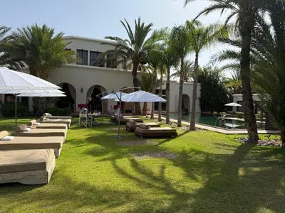 a row of chaise lounges and umbrellas next to a resort at Palais FARAH in Marrakech