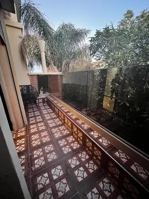 a view of a patio with a fence and palm trees at Villa Al Nour avec piscine in Marrakech