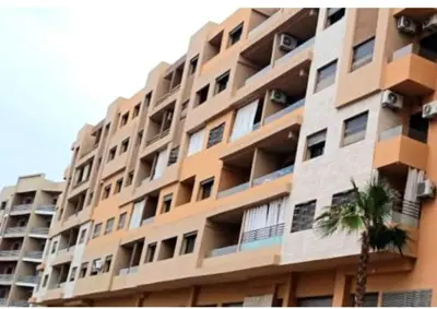 a large apartment building with a palm tree in front of it at Super appartement haut standing ensoleillé gare in Marrakech