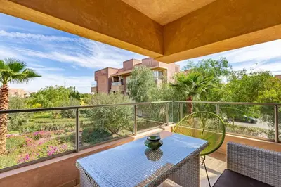 a patio with a table and chairs on a balcony at Golf Prestigia, grande piscine, jardins in Marrakech