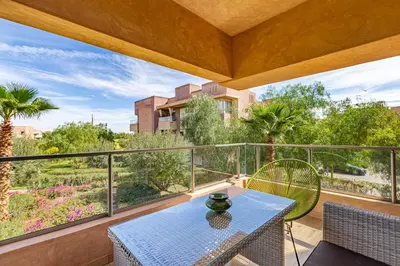 a patio with a table and chairs on a balcony at Golf Prestigia, grande piscine, jardins in Marrakech