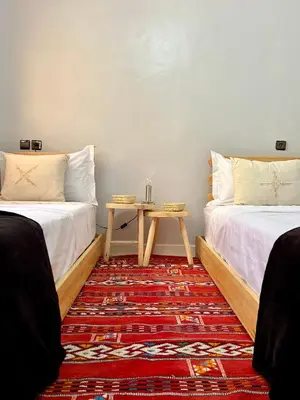 a room with two beds and a table on a rug at Cozy Apartment In Marrakech in Marrakech