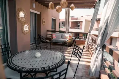 a patio with a table and chairs on a balcony at Appartement Luxe Riad Garden Marrakech 3 piscines in Marrakech