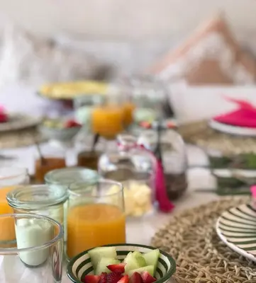 a table with a plate of fruit and glasses of orange juice at Riad Fisaline en exclusivité pour vous à Marrakech in Marrakech