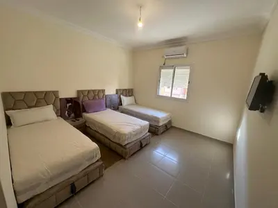 a small bedroom with two beds and a tv at Marrakech airport apartment in Marrakech
