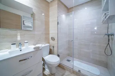 a bathroom with a toilet and a glass shower at Central & comfy 3BR apartment with pool & wifi access in Marrakech