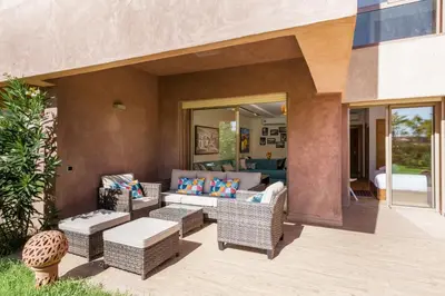 a patio with wicker furniture and a living room at Apart Confort Front Pool-Garden in Marrakech