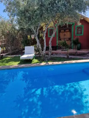 a pool in front of a house with a chair at Manzal Lahbab, 2Villas 2Bungalows 2Piscines et Jardins in Marrakech