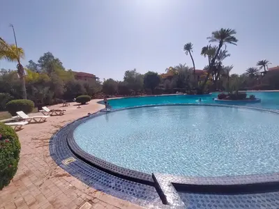 a large swimming pool in a resort with palm trees at Appartement HIBISCUS 3 chambres avec piscine in Marrakech