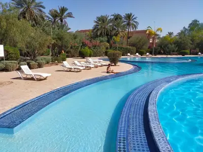 a pool with lounge chairs and a person sitting in the middle at Appartement HIBISCUS 3 chambres avec piscine in Marrakech