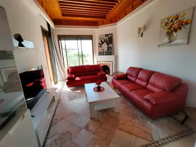 a living room with a red couch and a table at Appartement HIBISCUS 3 chambres avec piscine in Marrakech