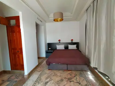 a bedroom with a bed in a white room at Appartement HIBISCUS 3 chambres avec piscine in Marrakech