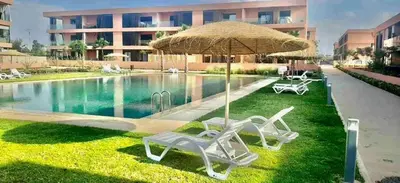two lawn chairs and an umbrella next to a swimming pool at Belle vue, noria golf in Marrakech