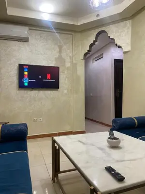 a room with a table and a tv on a wall at Confort Abordable Louez Notre Appartement in Marrakech