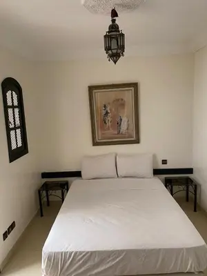 a bedroom with a white bed and a chandelier at Riad Nour Resorts in Marrakech