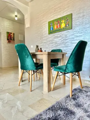 a dining room with a table and four green chairs at Appartement Denda in Marrakech
