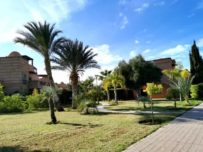 a park with palm trees and a sidewalk at Cozy apartment with roof top in Marrakech
