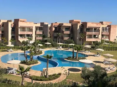 a resort with a pool with umbrellas and palm trees at New appart, pool and golf view in Marrakech