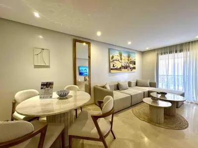 a living room with a couch and a table and chairs at Appart de standing + piscine sur le toit in Marrakech