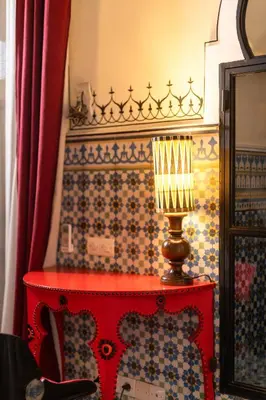 a red table with a lamp next to a wall at Riad Bindoo & Spa in Marrakech