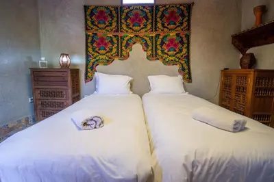 a bedroom with two beds with white sheets at La Ferme de LallaDom in Tameslouht