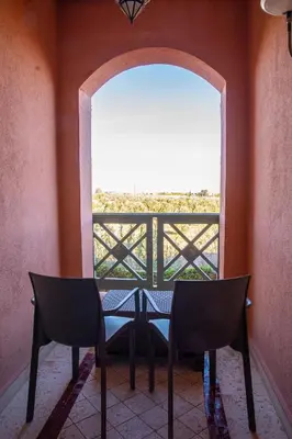 a table and two chairs in a room with a window at Tibouda House Deluxe Avec Piscine - Familiale in Marrakech