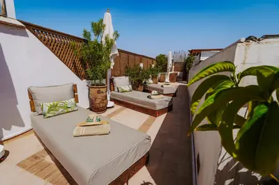 a patio with a couch and chairs on a balcony at Riad Assouel et Spa By La Siredrah in Marrakech