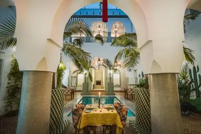 a dining room with a table and a pool at Riad Assouel et Spa By La Siredrah in Marrakech