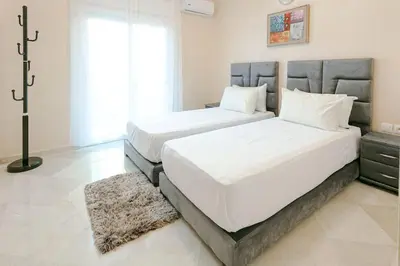 two beds in a bedroom with white sheets at Modern Odyssey – Marrakech Centre in Marrakech