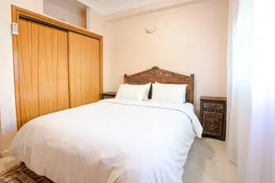a bedroom with a white bed with a wooden headboard at Modern Odyssey – Marrakech Centre in Marrakech