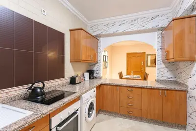 a kitchen with wooden cabinets and a washer and dryer at Modern Odyssey – Marrakech Centre in Marrakech