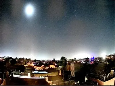a view of a city at night with the moon at Ryad Laârouss in Marrakech