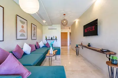 a living room with a blue couch and pink pillows at luxueux & spacieux appartement a prestigia in Marrakech