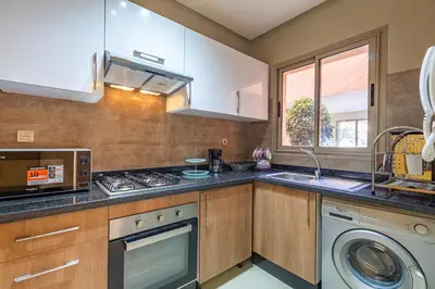 a kitchen with a sink and a stove and a microwave at luxueux & spacieux appartement a prestigia in Marrakech