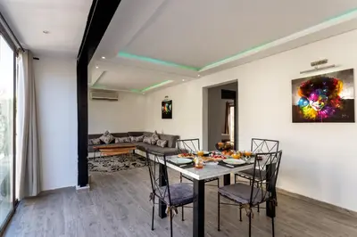 a dining room and living room with a table and chairs at Villa privée avec piscine Sans vis-à-vis, calme absolu in Marrakech