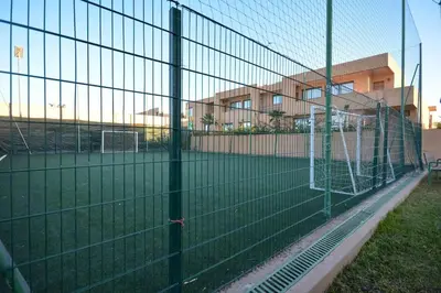 a fence with a soccer field behind a building at Luxueux Duplex 2CH dans une magnifique résidence in Marrakech