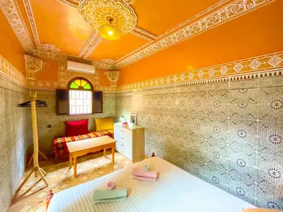 a room with a bed and a bedroom with orange walls at Dar Amane - Charmante maison marocaine in Marrakech