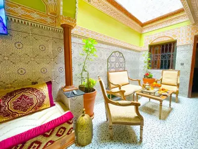 a bedroom with a bed and two chairs and a table at Dar Amane - Charmante maison marocaine in Marrakech