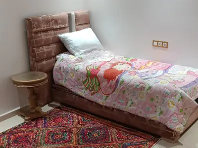 a bed with a blanket and a stool next to a rug at Chez bousfyha in Marrakech